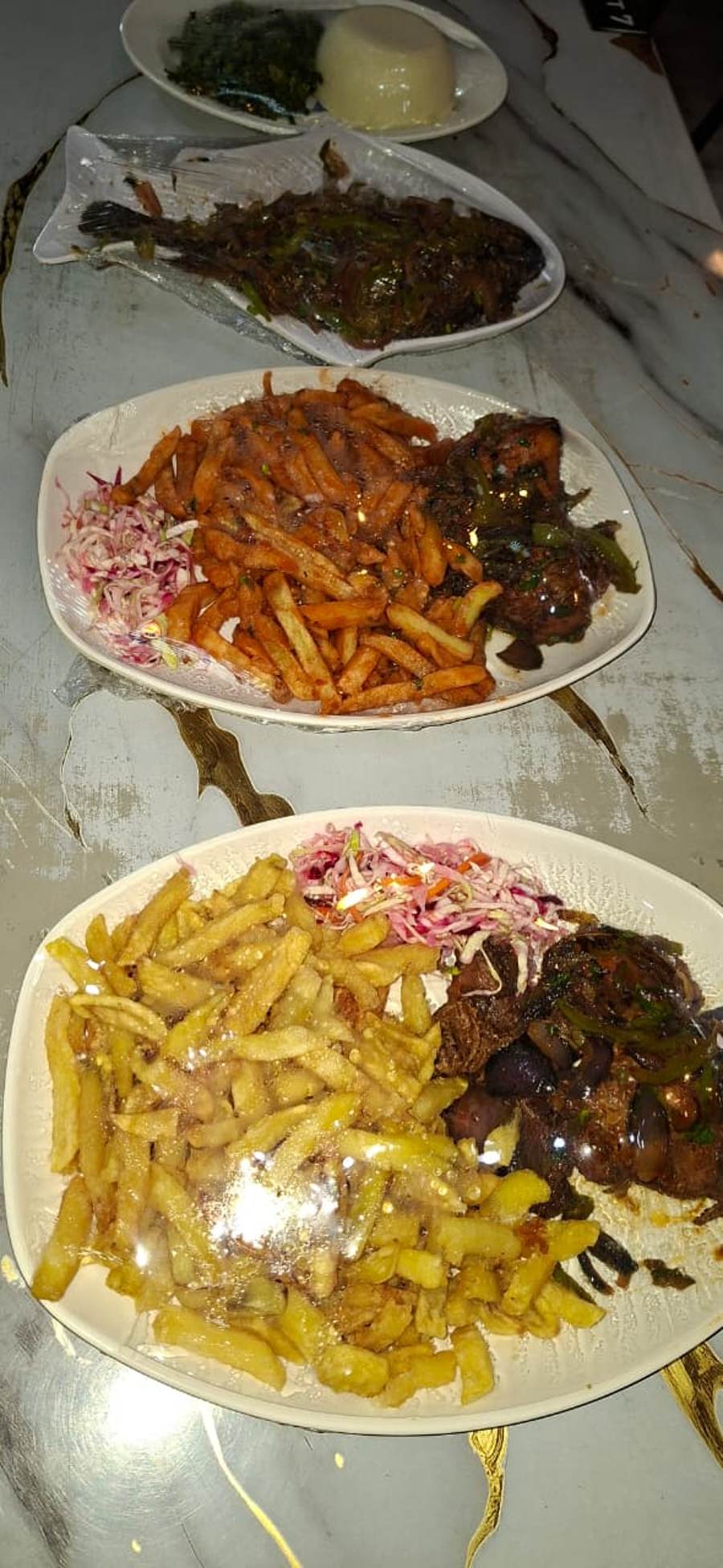 Table spread of mixed grill, whole fish and chips